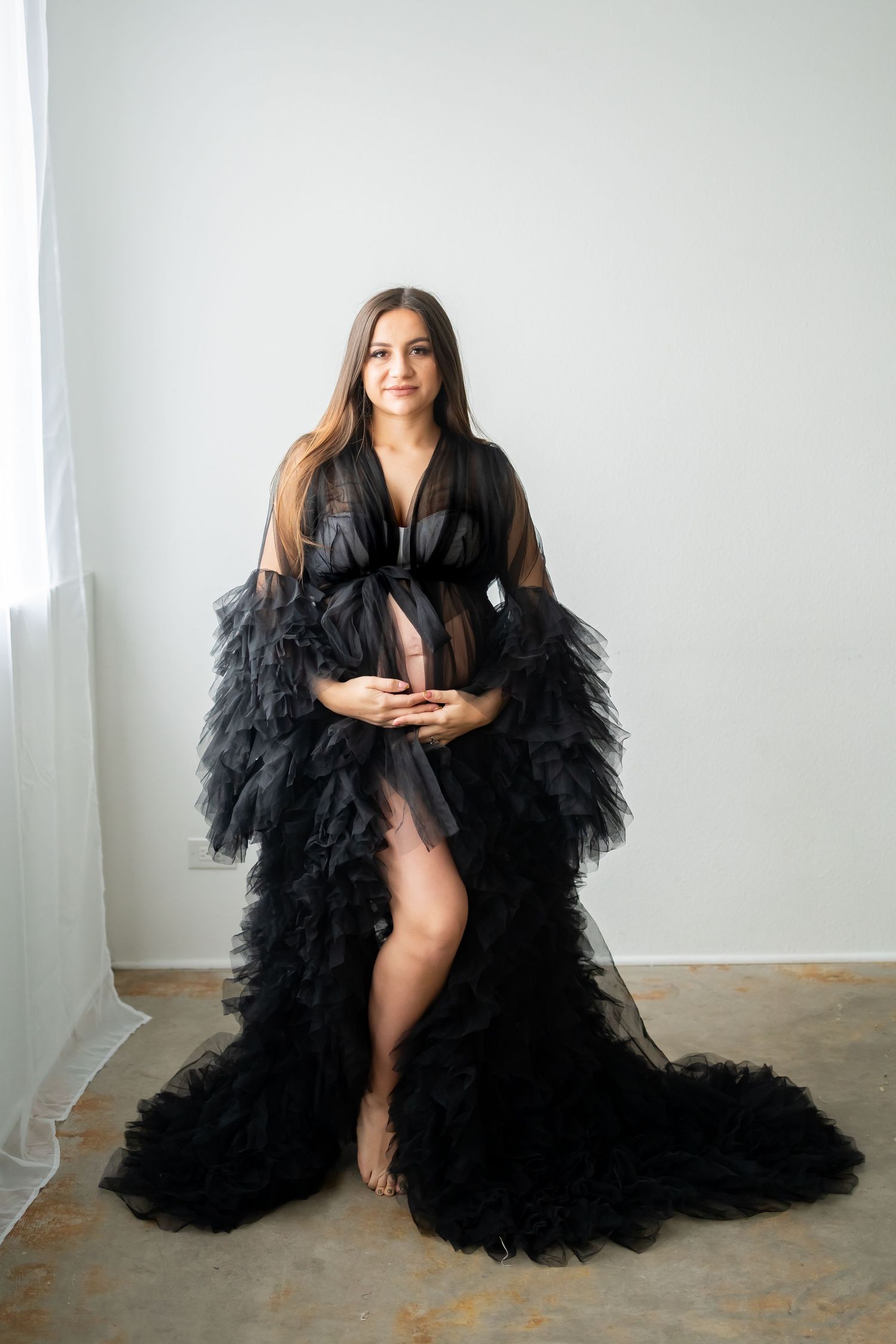 Ethereal maternity portrait in black ruffled tulle gown with dramatic train.