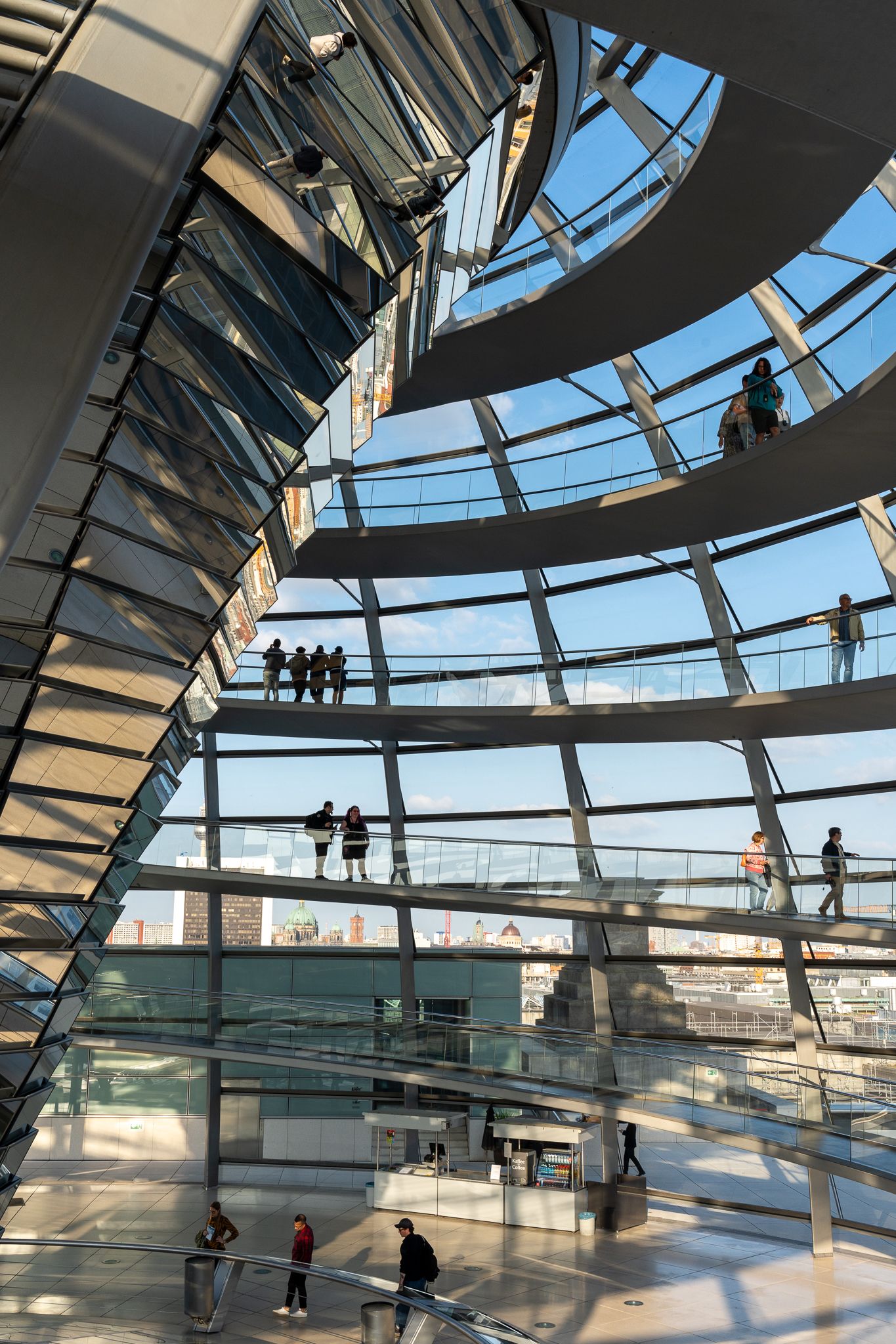Spiral walkway inside the glass dome of the Reichstag building in Berlin with visitors exploring different levels.