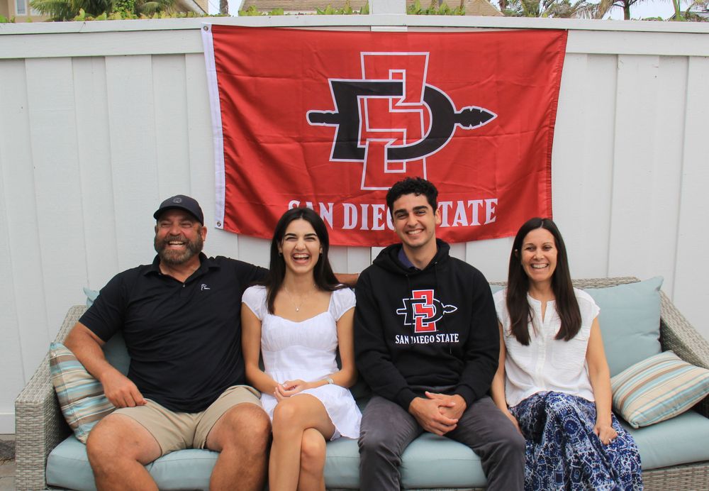 San Diego State University logo flag with group sitting on outdoor patio furniture.