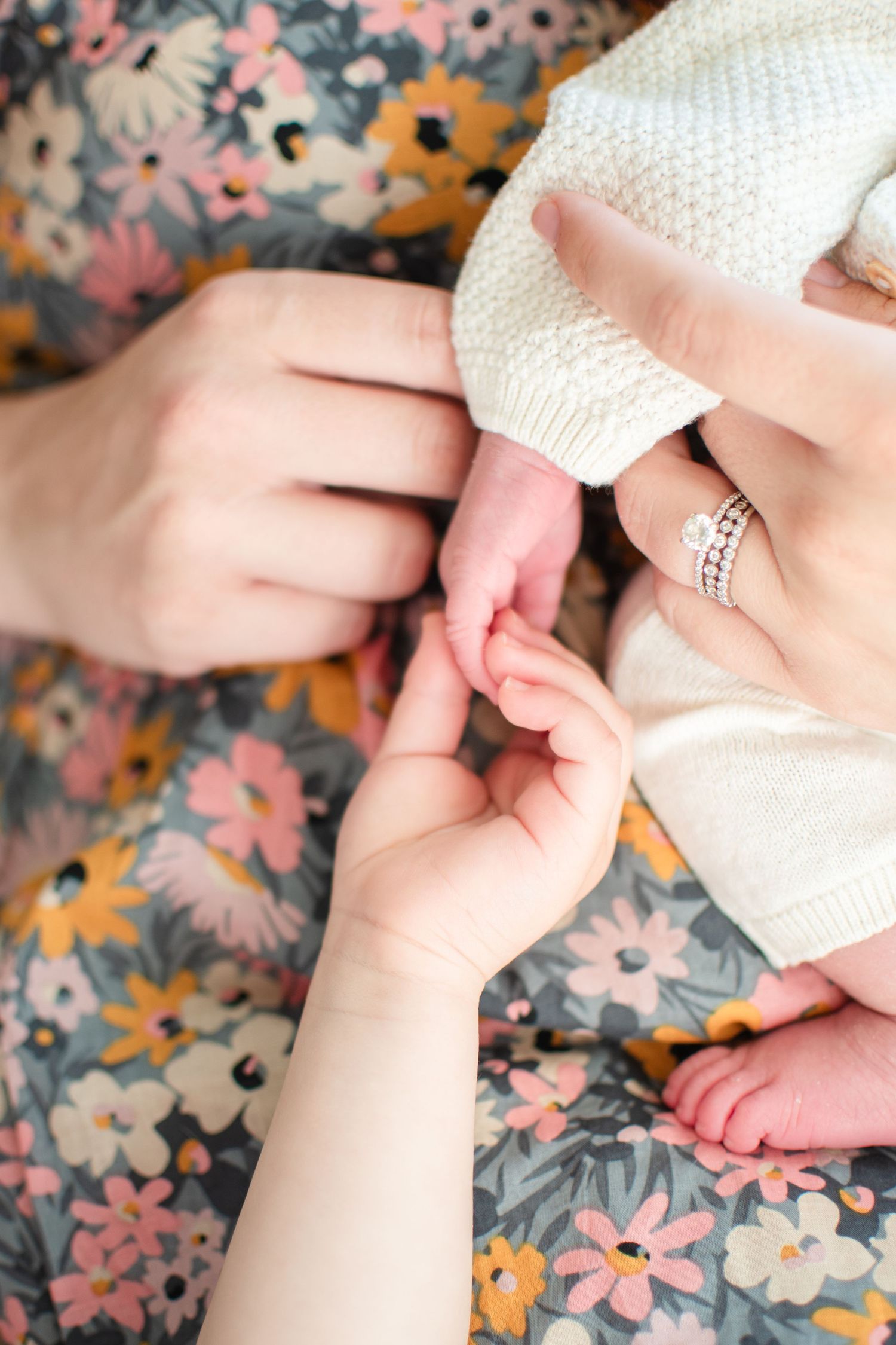 Big sister reaches up to grab her newborn sister's tiny fingers.