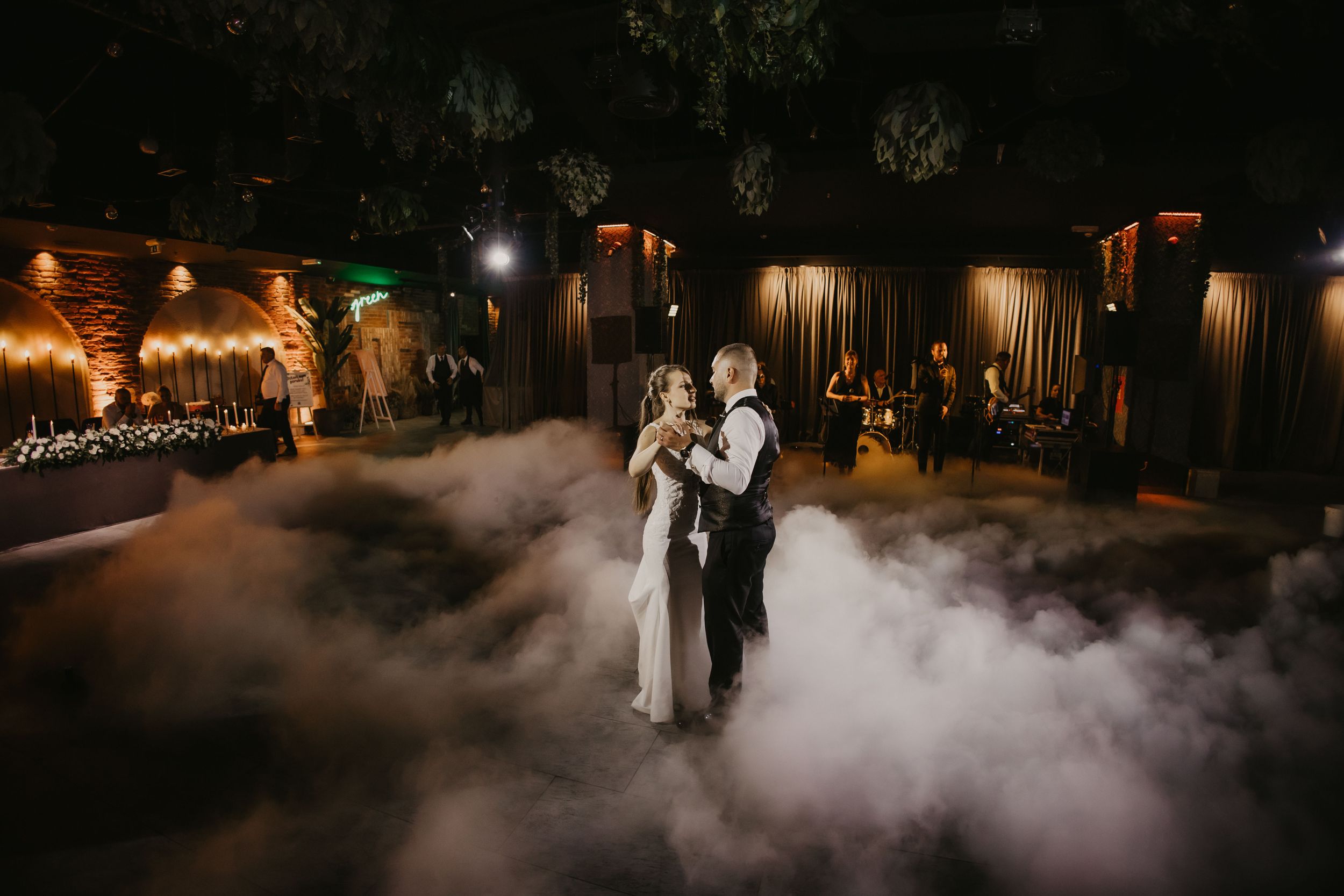 Romantic first dance with atmospheric fog and ambient lighting at indoor wedding venue.