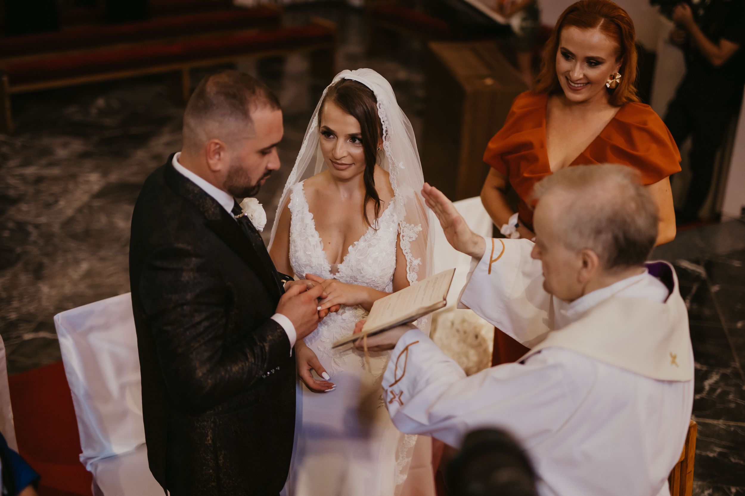 A wedding ceremony takes place in a traditional church setting with warm lighting.