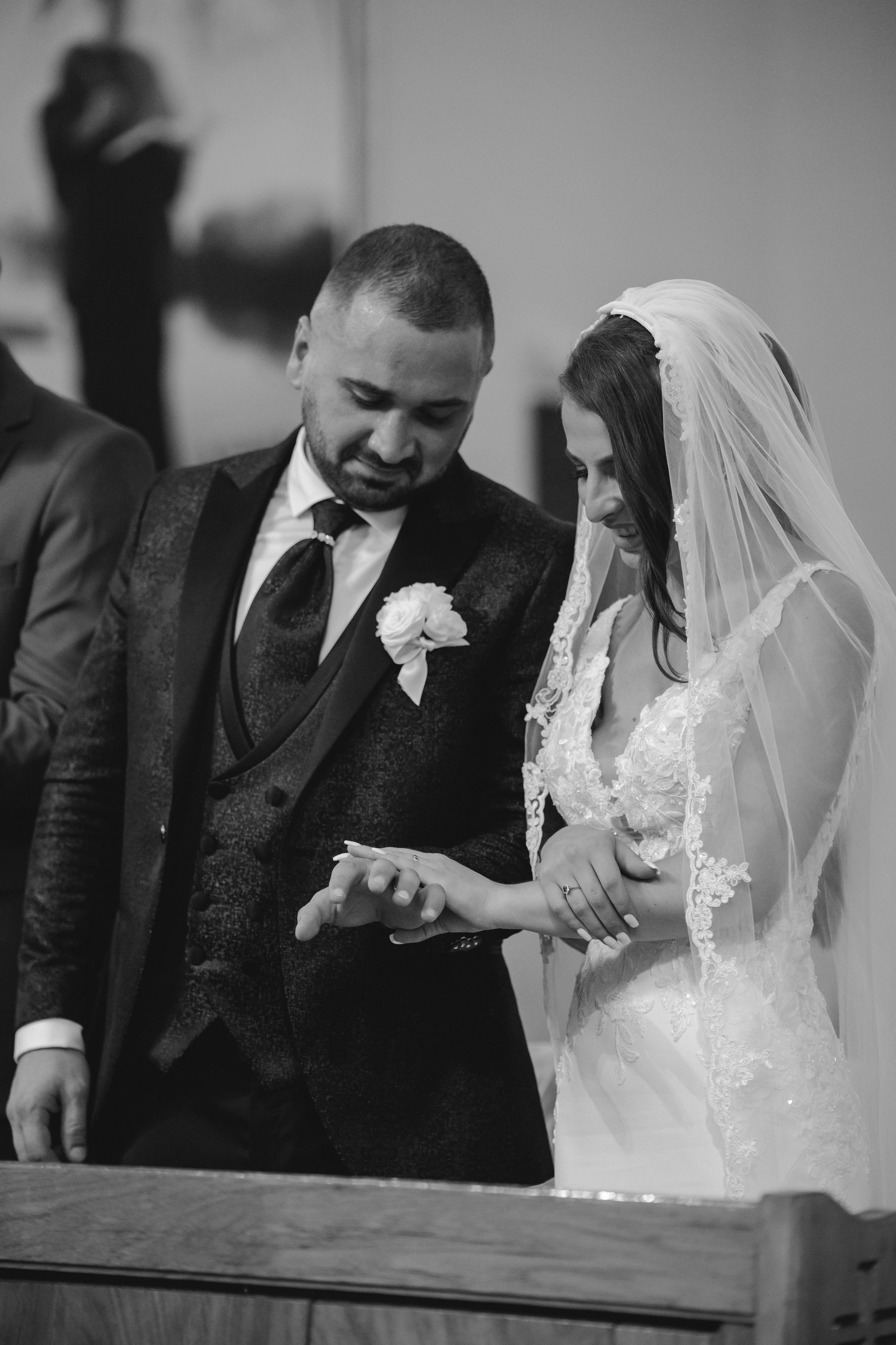 A touching black and white moment during a wedding ceremony as couple exchanges rings.