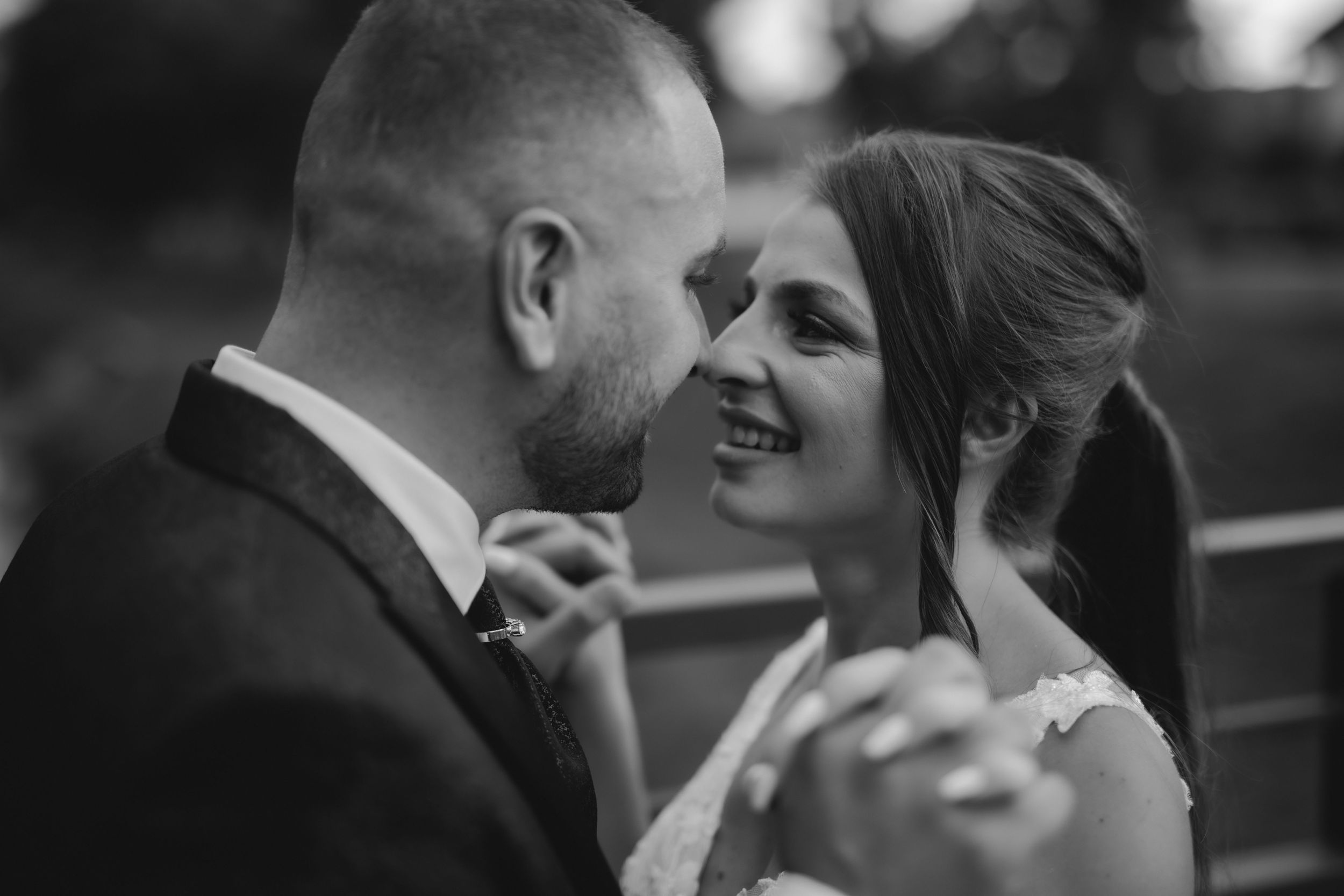 An intimate black and white portrait captures a tender moment between newlyweds.