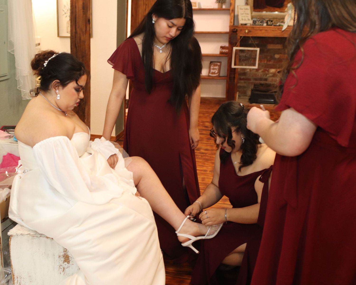 Bridal party members in red dresses help prepare the bride in a white gown before the wedding ceremony.