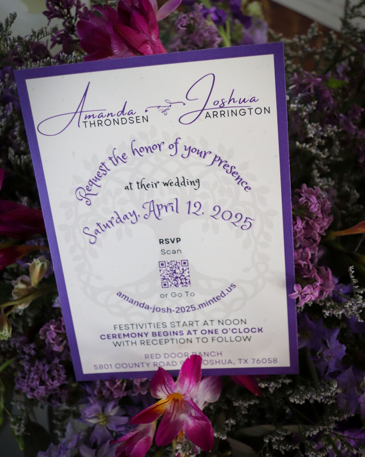 Purple wedding invitation with cursive text surrounded by magenta and purple flowers.