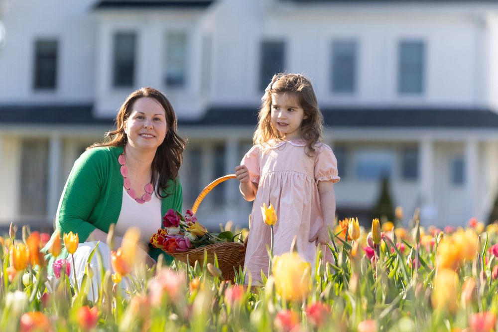 Mother and Daughter post in the tulip field at Ferjulian's Farm during a spring family photo session by  Lisa West Photography