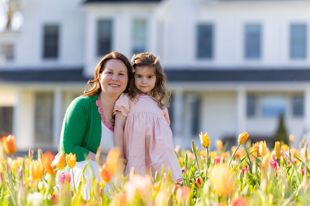 Mother and Daughter post in the tulip field at Ferjulian's Farm during a spring family photo session by  Lisa West Photography