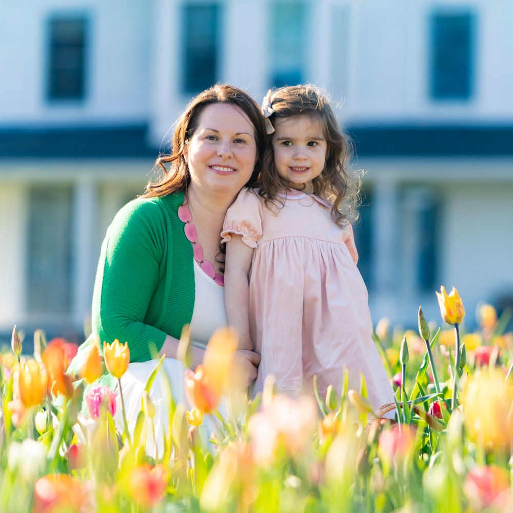Mother and Daughter post in the tulip field at Ferjulian's Farm during a spring family photo session by  Lisa West Photography