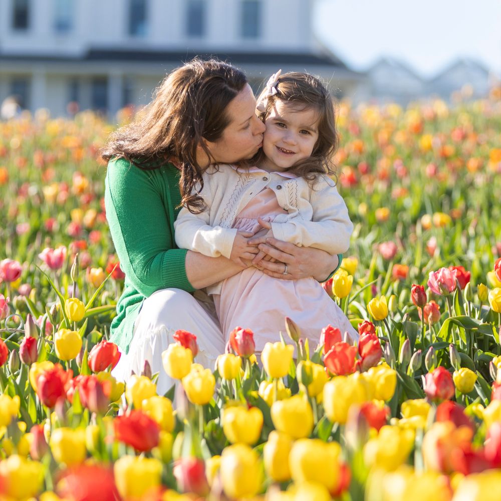 Mother and Daughter post in the tulip field at Ferjulian's Farm during a spring family photo session by  Lisa West Photography