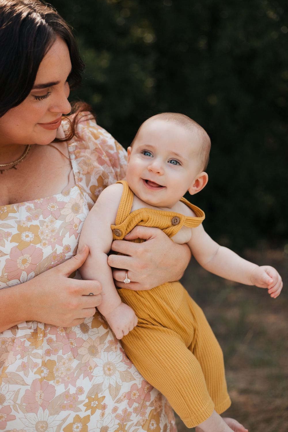 Joyful moment captured between parent and laughing baby in yellow knit outfit.
