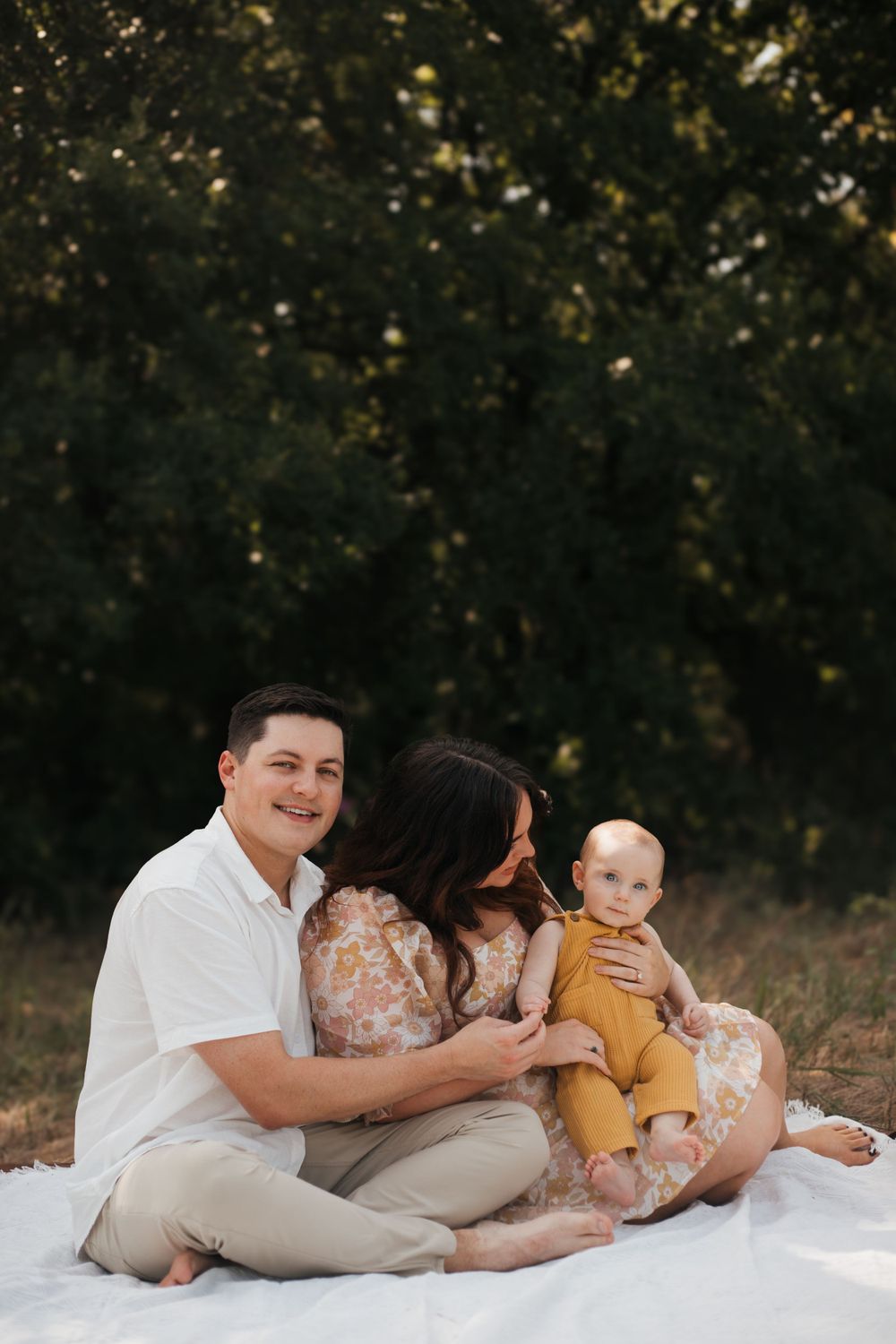 Family sitting together on white blanket during sunset photo session.