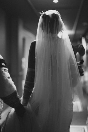Black and white photo showing silhouette of bride with flowing veil.