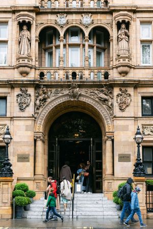 Grand Victorian entrance of Kimpton Fitzroy London with ornate stone carvings and arched doorway.