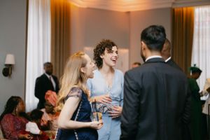 Wedding guests socializing and laughing at an elegant indoor reception.