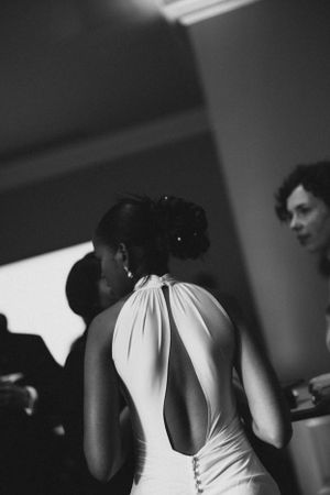 Elegant white backless dress captured in dramatic black and white photography at a formal event.