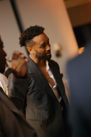 A stylish guest in a dark suit jacket mingles at an evening celebration.