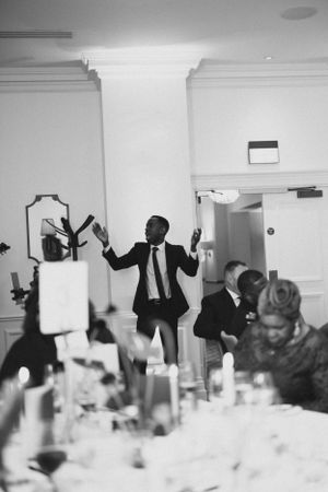 Black and white photo capturing energetic dancing and celebration at a formal reception.