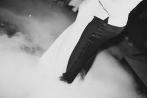 Black and white photo capturing bride's dress flowing in misty atmosphere.