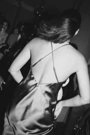 Back view of woman in satin dress dancing at formal event.