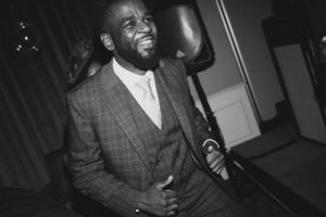 Person in grey plaid suit smiling at formal event.