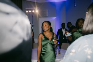 Guest in emerald satin dress enjoys reception party atmosphere.