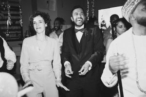 A joyous black and white photograph capturing a wedding celebration with guests dancing and smiling.