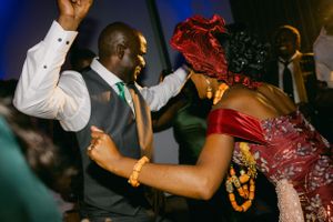 Two wedding guests dancing enthusiastically in formal attire at a reception.