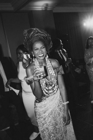 Woman in traditional African attire and headwrap dances joyfully at celebration.
