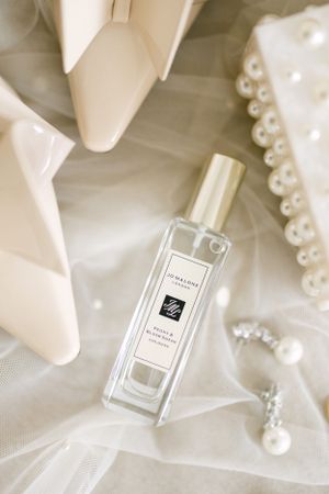 Jo Malone perfume bottle and pearl accessories elegantly displayed on white tulle.