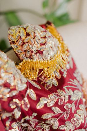 Intricate gold and crystal beadwork details on a deep red traditional wedding dress.