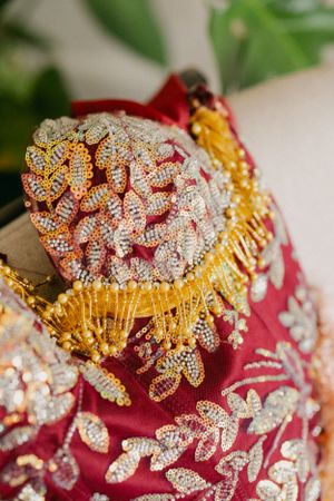 Ornate red and gold embroidered fabric with crystal embellishments and metallic trim.