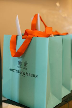 Iconic turquoise Fortnum & Mason shopping bags with orange ribbon handles.
