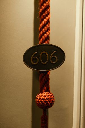 Room number 606 displayed on oval plaque with decorative red rope detail.