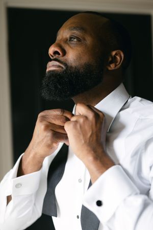 Wedding preparation photo showing formal white dress shirt and bowtie adjustment.