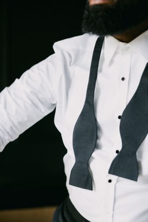 Close-up detail of a black bow tie against a crisp white dress shirt.