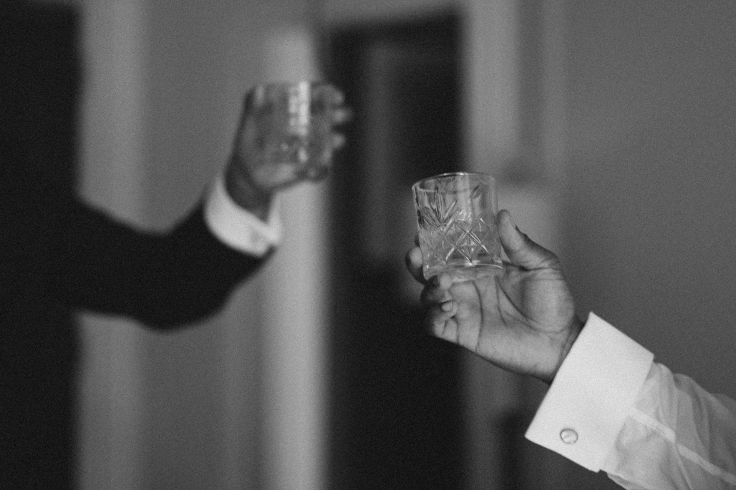 Two hands holding crystal glasses in a celebratory toast.