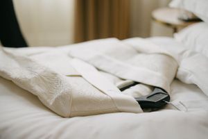 White dress shirt and tie laying on crisp white bedding.