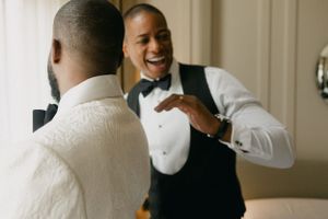Two people in formal attire sharing a joyful moment while getting ready.