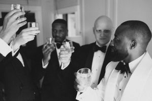 A black and white photograph of formally dressed men raising glasses in a toast.