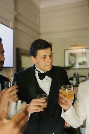 Guests in tuxedos enjoying drinks during formal celebration.