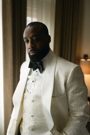 An elegant white tuxedo with textured fabric and black bow tie being worn in a formal setting.