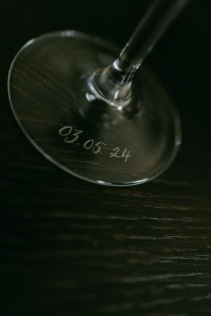Close-up of a wine glass base with the date 03.05.24 etched on it.