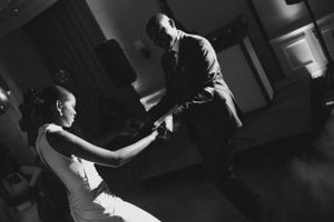 Black and white photo of couple dancing intimately at wedding reception.