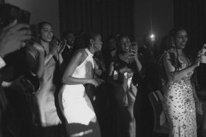 Black and white photo of wedding guests dancing and celebrating on dance floor.