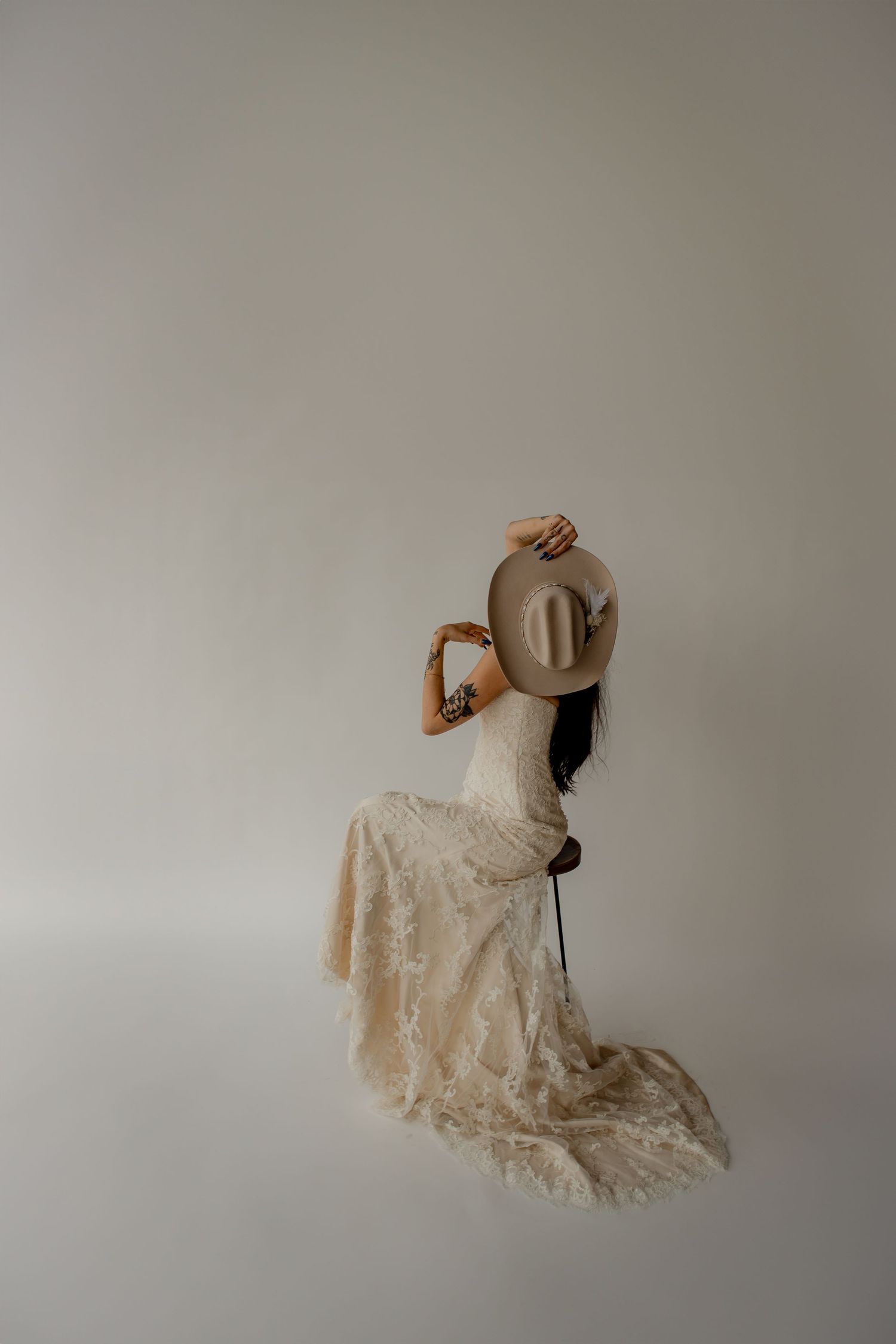 Artistic portrait of someone in a vintage lace wedding dress holding a cowboy hat.