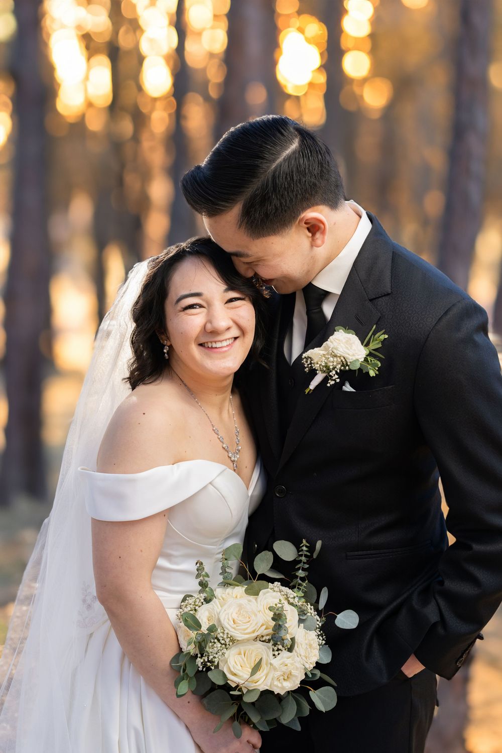 Romantic wedding couple shares intimate moments at sunset with glowing bokeh lights in the background.