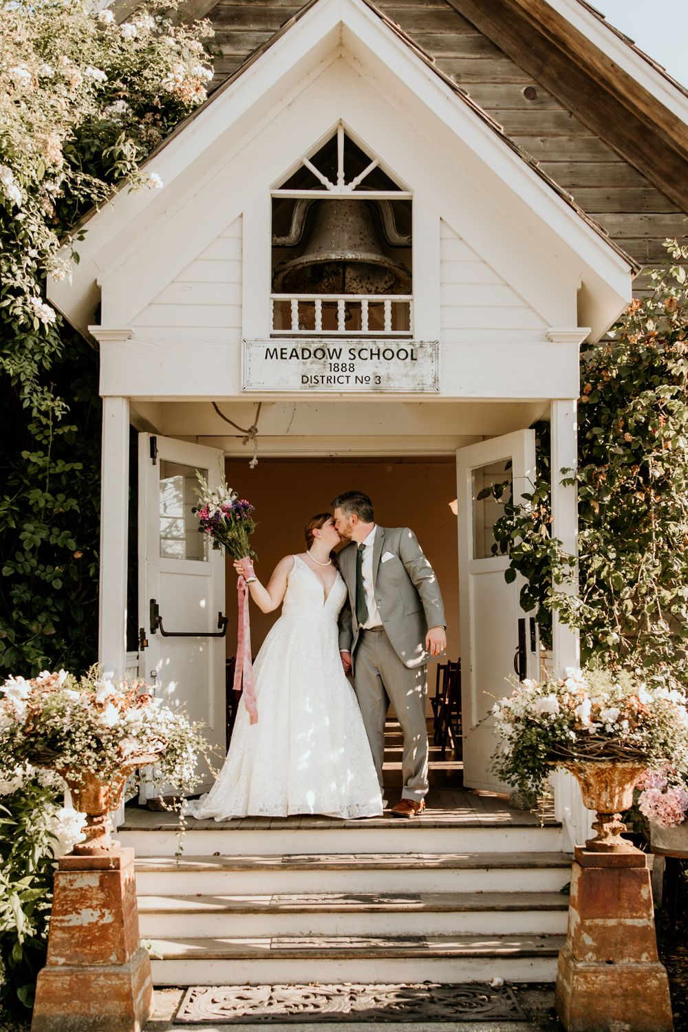Bride and groom kiss on the porch of an 1800's schoolhouse