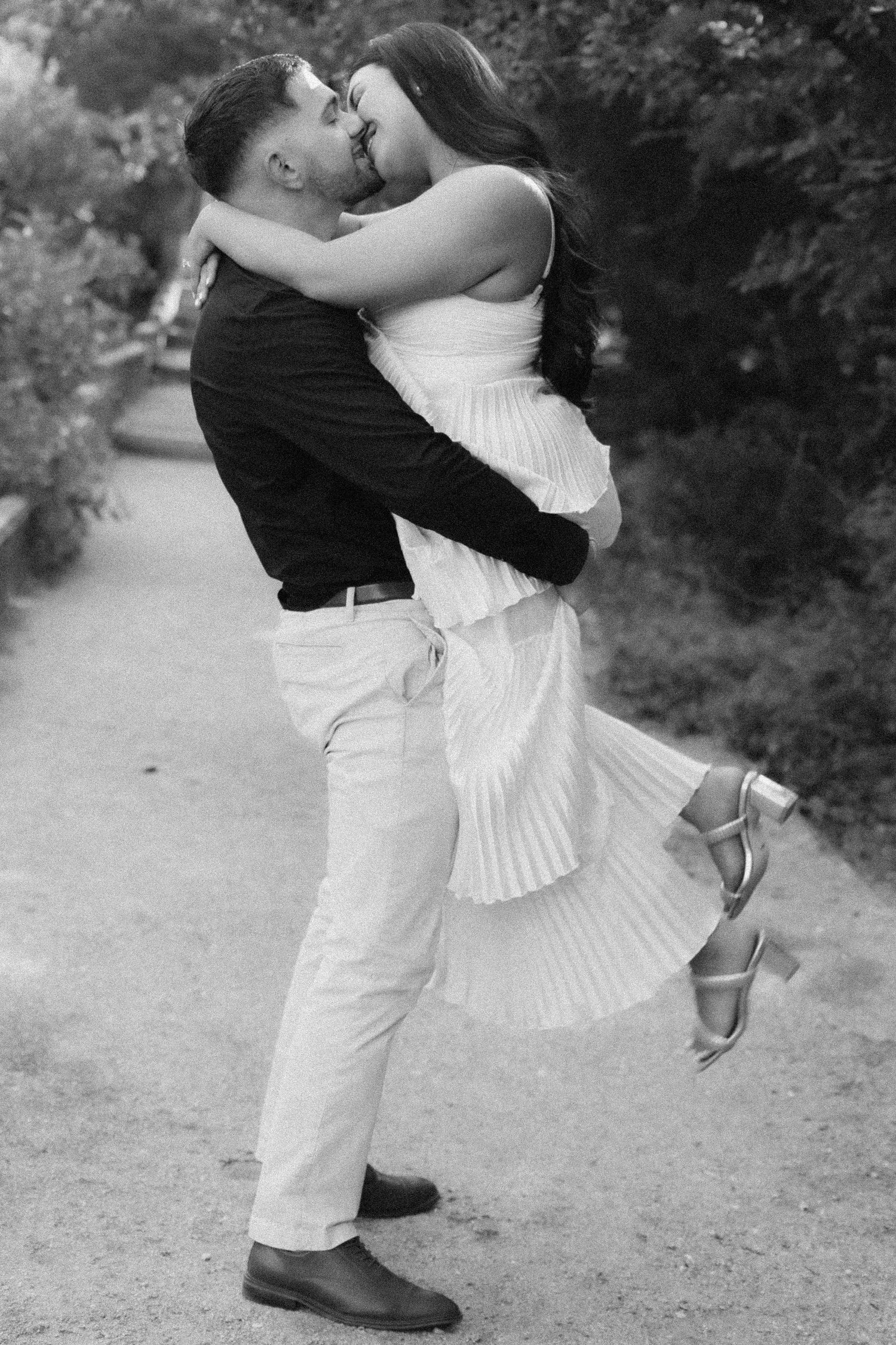 A romantic black and white photo of a couple embracing in a whimsical outdoor setting.