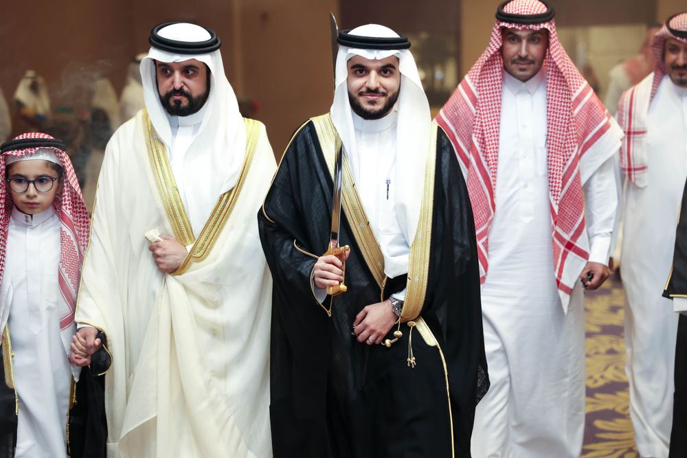 لحظة دخول العريس إلى قاعة الزفاف في الرياض، يظهر في الصورة وهو يسير بثقة وأناقة حاملا سيف العرضى.